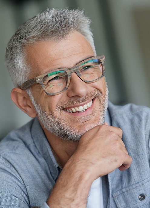 A smiling middle-aged man wearing trendy eyeglasses