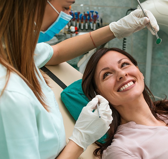 A dentist chatting with her happy and smiling patient