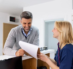 Dental receptionist helping patient at front desk