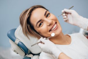 Woman smiling as dentist holds mirror and pick up to her teeth