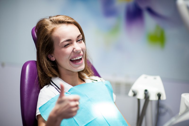 A woman giving a wink and a thumbs up at a dentist’s office